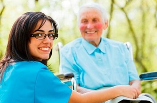 Kind nurse taking care of elderly lady patient in wheelchair.