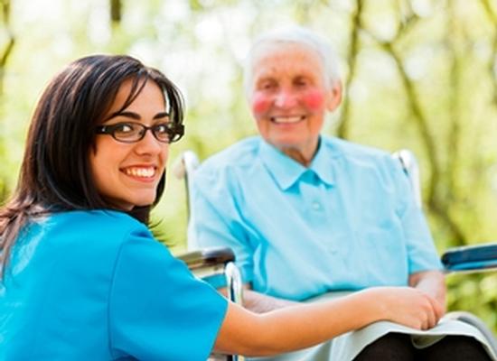 Kind nurse taking care of elderly lady patient in wheelchair.